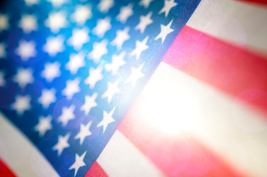 USA flag background, design template. American flag blurred texture with glare and blue lens flare effect, selective focus, mixed media.
