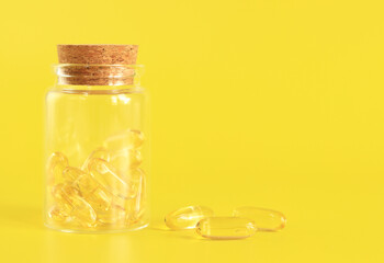 Omega-3 capsules in a glass bottle on a yellow background. Health care, medical pills and nutritional supplements. Health concept. Unsaturated fatty acids Omega-3