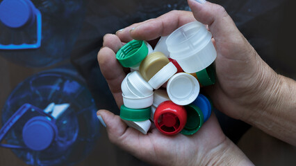 Woman hands holding many plastic bottle lids in different colors. Concept of water pollution and...