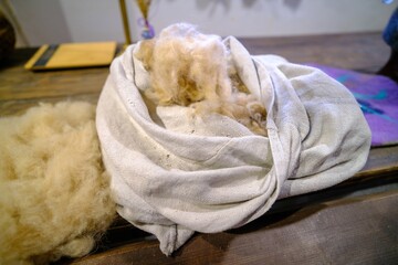 White, soft and fluffy sheep's wool in a white fabric bag
