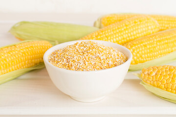 Corn groats with fresh cobs on wooden table