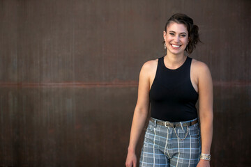 Portrait of a unique and stylish artist, standing in front of a large rustic metal wall, copy space