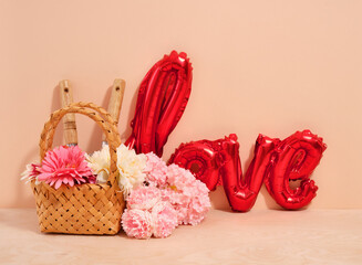 Wicker decorative basket with flowers and garden tools. Red foil balloon in the form of the word love.