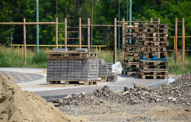 construction site with empty pallets and stacks of paving slabs. repair and construction of new facilities in the city park. paving walkways