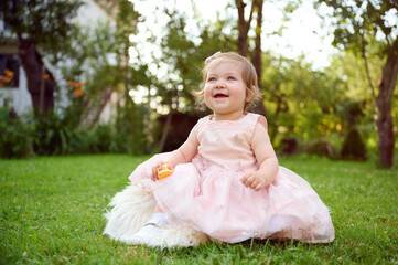 Adorable girl on the grass in the garden. Close up portrait. Happy little girl in summer scenery....