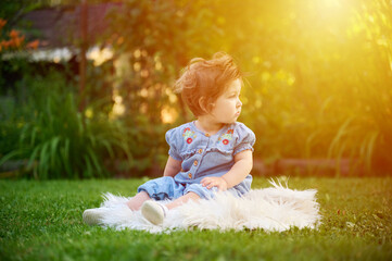 Adorable girl on the grass in the garden. Close up portrait. Happy little girl in summer scenery....