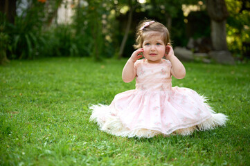 Adorable girl on the grass in the garden. Close up portrait. Happy little girl in summer scenery....