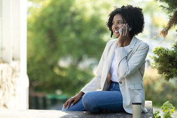 Attractive corporate businesswoman have phone call, sitting on stairs