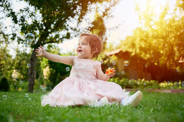 Adorable girl on the grass in the garden. Close up portrait. Happy little girl in summer scenery....