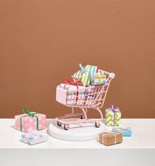 The pink shopping cart is littered with gifts of various sizes. Sale concept and waste of money.