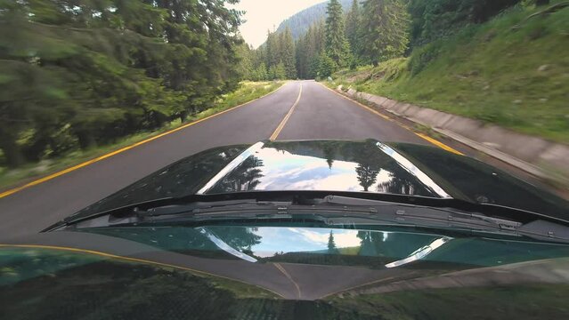 Car ride Point Of View, The Majestic Transalpina Mountain Road in Romania With A Black sport Car Bonnet In The Foreground And Tall Mountain Peaks. POV shot of sport car drives along the majestic and