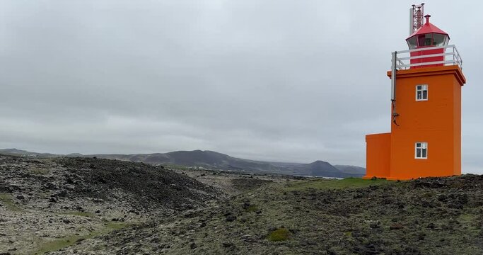 Pretty orange Hopsnes Lighthouse near Grindavik, Iceland on the Reykjanes Peninsula. Side panning establishing shot
