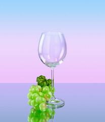 A wine or champagne glass and a bunch of ripe, tasty, juicy green grapes on table.