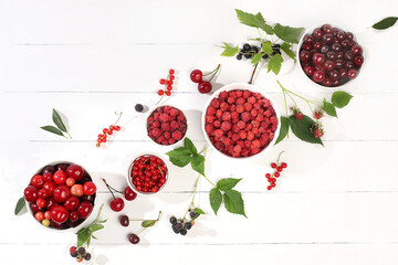 Summer fresh cherries, currants and raspberries on a light wooden background with leaves, banner...