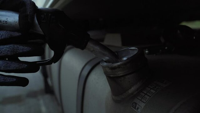 Refueling a truck with diesel fuel at a gas station. The driver inserts a refilling gun into the truck's fuel filler.