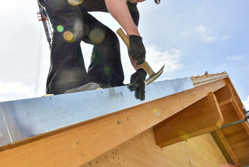Montage des Ortgangblechs durch den Dachdecker am äusseren Sparren der Giebelseite des Steildachs...