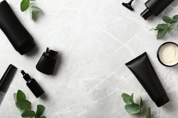 Frame of men's skin care products in black bottles with green leaves on stone background. Premium...