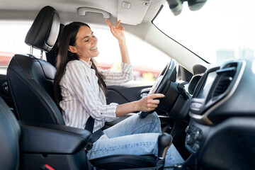 Happy pretty young woman driving car, listening to music