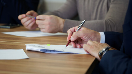 A man signs a document during a business meeting or negotiations. Signing an order, deal, memorandum, agreement or contract. No face. Selective focus - obrazy, fototapety, plakaty