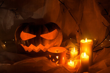 Happy Halloween! Spooky Jack o lantern carved pumpkin, spider web, ghost, bats and glowing light in dark. Scary atmospheric halloween party decorations, space for text. Trick or treat