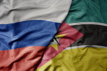 big waving realistic national colorful flag of russia and national flag of mozambique .