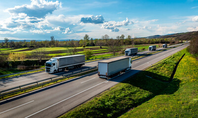 Convoys of white transportation Trucks in lines passing other trucks on a rural countryside highway...