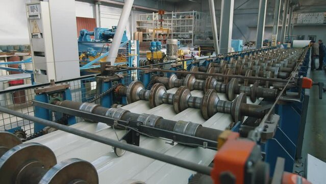 View of metal sheet forming machine in metalwork factory. Steel rollers in metalforming machine for production roof tile in factory