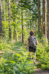 hiker girl on her back walking in bavarian forest on sunny day