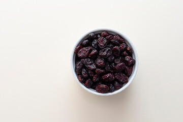 Top View Superfood Heap Of Dried Cranberries In White Bowl On Beige Background. Copy Space. Sweet Dehydrated Cranberries. Nutrients And Vitamins. Horizontal Plane.