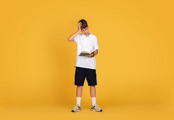 Fototapeta na wymiar Confused sad tired caucasian teenager boy reading book, puts hand to head