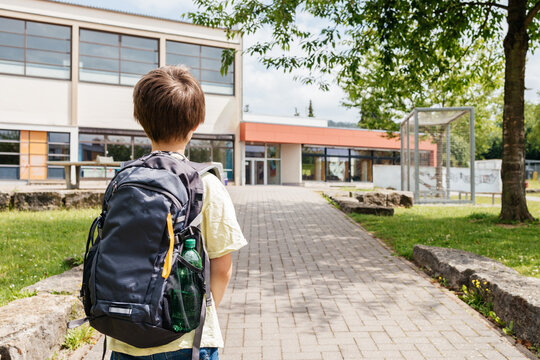 Back view of a boy with a backpack on his back going to school. Back to school. Beginning of the school year and school hours.