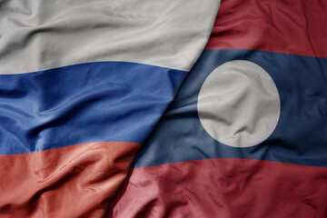 Fototapeta premium big waving realistic national colorful flag of russia and national flag of laos .