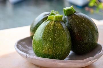 Round green courgette or zucchini, on wicked plate, close up, healthy food