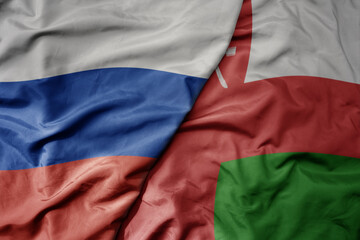 big waving realistic national colorful flag of russia and national flag of oman .