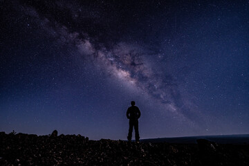 Naklejka na ściany i meble Silhouette of Men / boy on the Milky Way. Stargazing at Mauna Loa Observatory Road, Big Island Hawaii. Starry night sky, galaxy astrophotography. 