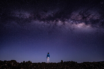 Naklejka na ściany i meble Woman on the Milky Way. Stargazing at Mauna Loa Observatory Road, Big Island Hawaii. Starry night sky, galaxy astrophotography. 