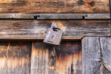 A rusted padlock on a wooden door.