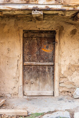 Fototapeta na wymiar A weathered wooden door in a mud walled home.