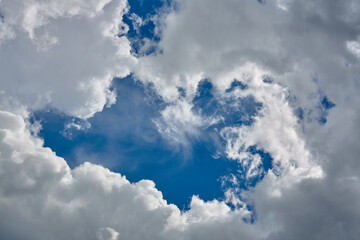 Cumulus clouds against a light blue sky with a clear fiber structure.