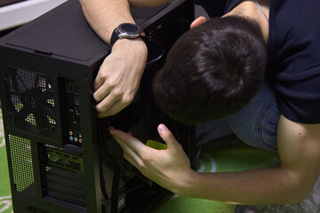 A young man, builds a new computer from components, cable management, the concept of assembling and repairing a computer