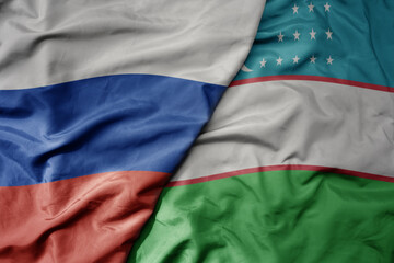 Obraz premium big waving realistic national colorful flag of russia and national flag of uzbekistan .
