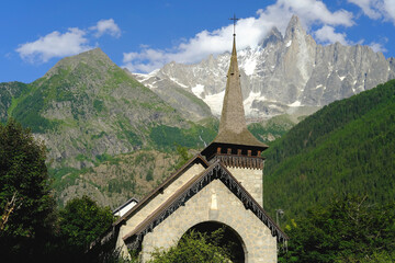 old little Chapelle, Les Praz Church in Chamonix-Mont-Blanc, building among green trees and high mountains, concept of travel, religion, mountain climbing