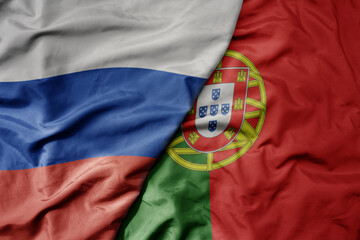 big waving realistic national colorful flag of russia and national flag of portugal .