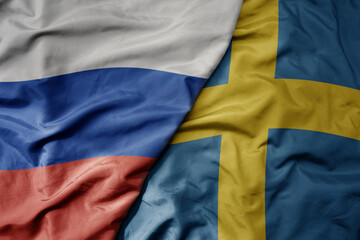 big waving realistic national colorful flag of russia and national flag of sweden .