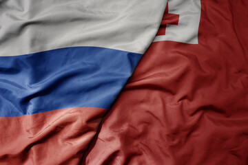 big waving realistic national colorful flag of russia and national flag of Tonga .
