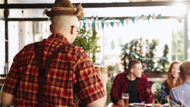 Young delightful people, friends meeting at pub in sunny day, drinking lager beer, celebrating festival, having fun. Concept of oktoberfest, traditional taste, friendship, leisure time, enjoyment