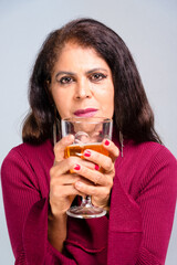 Attractive brunette holding a glass with beer. Studio photo. Isolated on gray background.