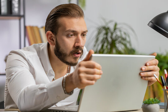 Irritated tired middle eastern business man while working on laptop, unexpected online website problem, computer virus data loss by hacking. Freelancer feeling mad, broken notebook at office workplace