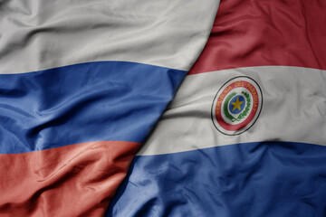 big waving realistic national colorful flag of russia and national flag of paraguay .