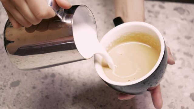 The barista steams the milk. The process of creating milk foam. Latte making process. latte coffee drink close-up barista whips milk in a pitcher with hot steam from a coffee machine.